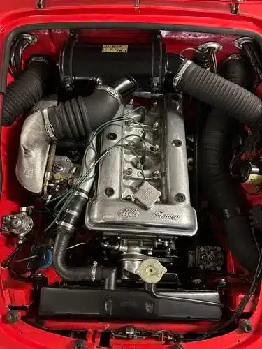 Motorraum eines gebrauchten Alfa Romeo mit sichtbaren technischen Details und leichter Patina