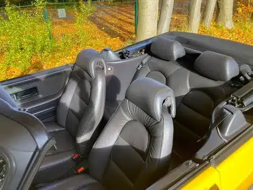 Detailaufnahme des Innenraums mit Ledersitzen eines gelben gebrauchten Cabrio-Sammlerfahrzeugs
