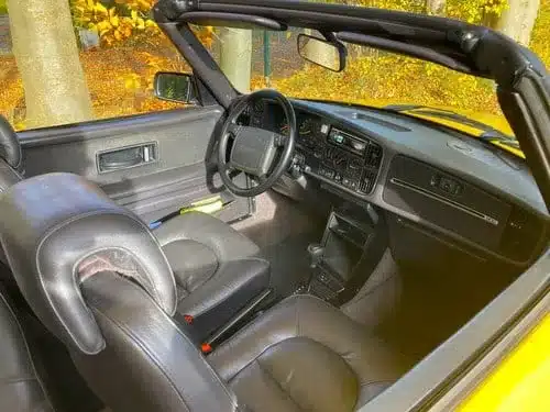 Gepflegter Innenraum eines klassischen Cabrios mit schwarzer Lederausstattung und offenem Verdeck