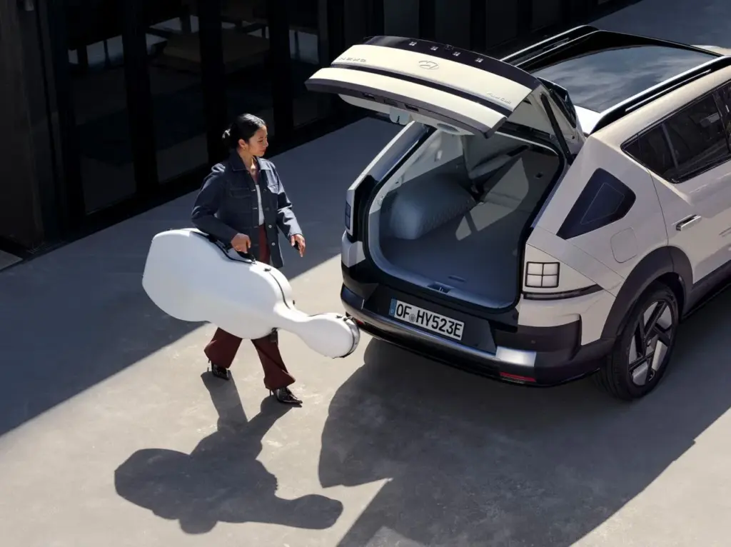 Frau stellt einen Cellokoffer in den offenen Kofferraum eines Hyundai SUVs