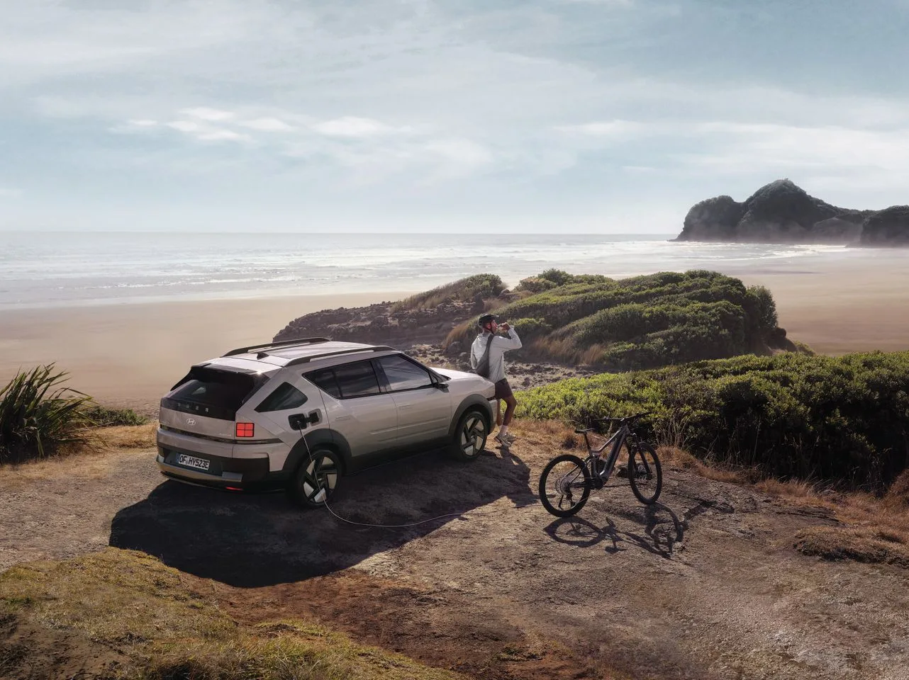 Hyundai Elektroauto lädt ein E-Bike am Strand über Vehicle-to-Load Funktion.