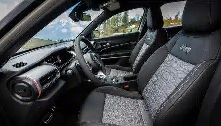 Innenansicht des Jeep Avenger 4xe Hybrid mit Armaturenbrett und vorderen Sitzen.