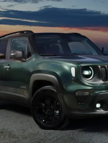 Grüner Jeep Renegade e-Hybrid mit einer Person am Fahrzeug vor abendlicher Landschaft.