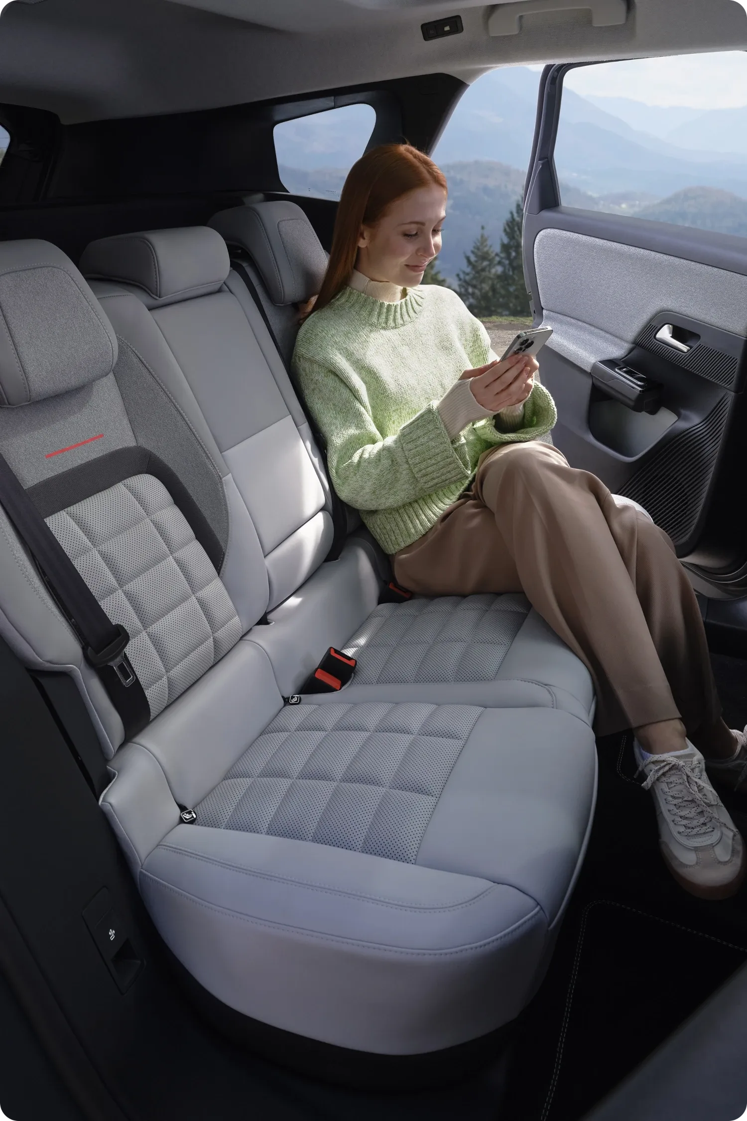 Frau sitzt entspannt auf den komfortablen Rücksitzen des Citroën C5 Aircross und nutzt ein Smartphone.