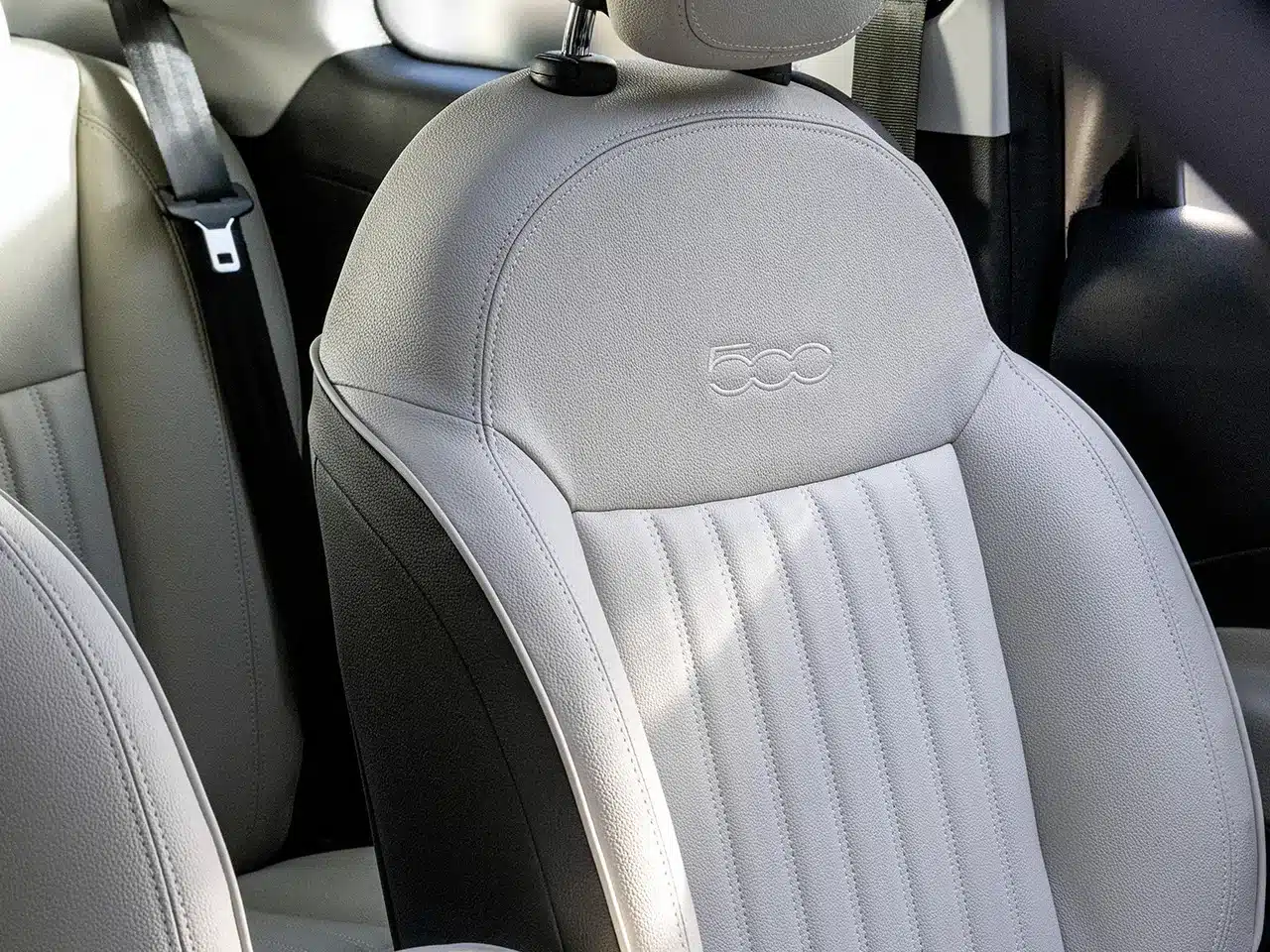 Detailansicht des hellen Vordersitzes im Fiat 500 Hybrid mit geprägtem 500-Logo.