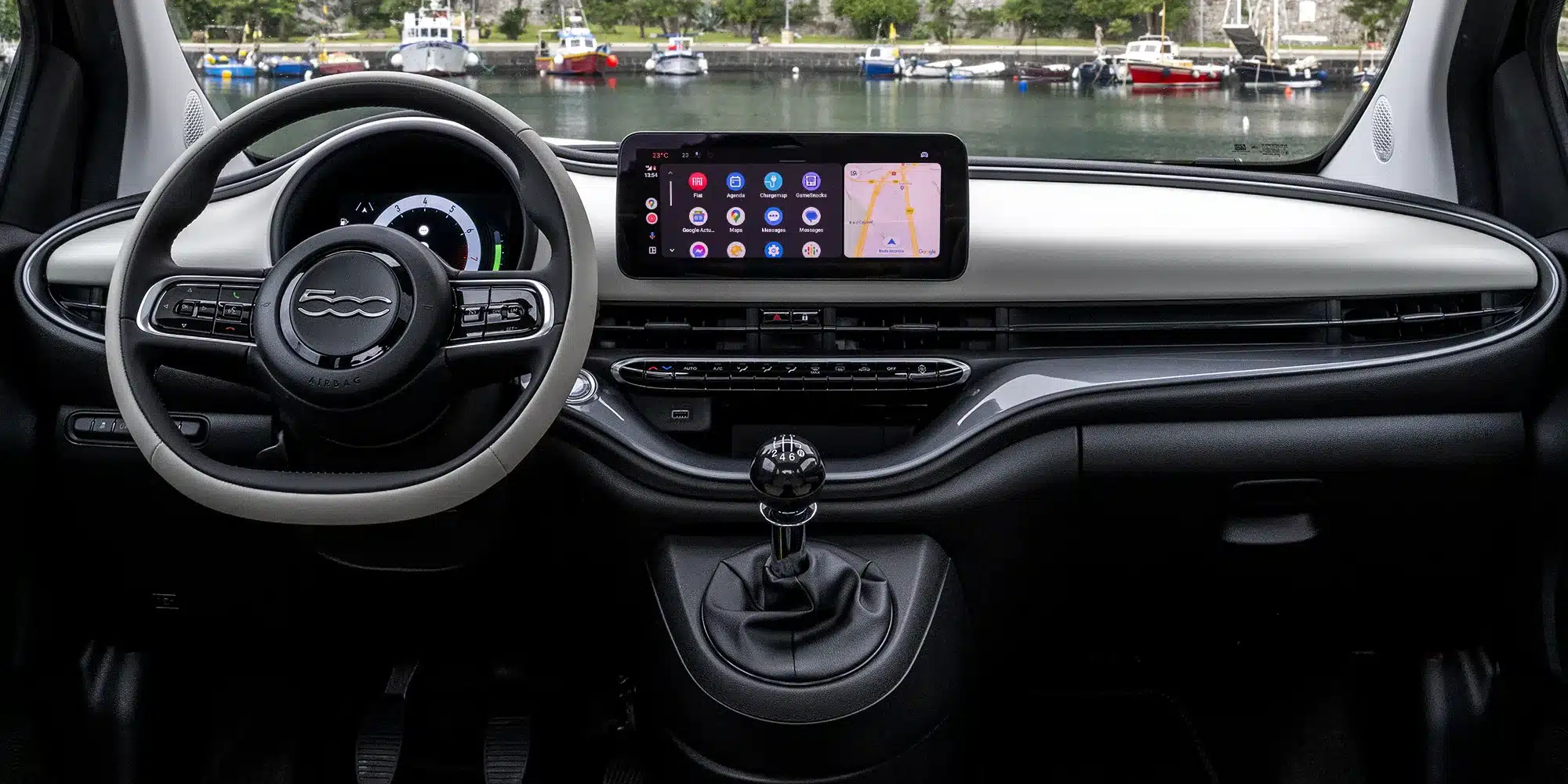 Innenraum des Fiat 500 Hybrid mit großem Touchscreen-Infotainmentsystem, Multifunktionslenkrad und manuellem Schaltgetriebe