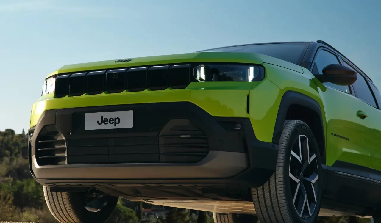 Frontansicht des Jeep Compass e-Hybrid in Grün mit markantem Kühlergrill und LED-Scheinwerfern