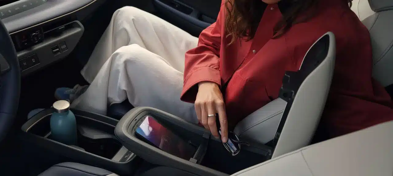 Innenraum des Nissan LEAF mit geöffneter Mittelkonsole, Smartphone und Trinkflasche