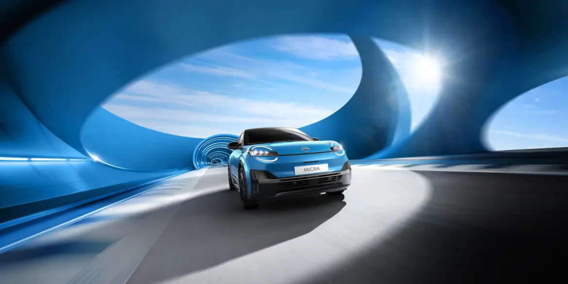Frontansicht des neuen blauen Nissan Micra beim Fahren durch einen modern designten blauen Tunnel mit Sonnenlicht