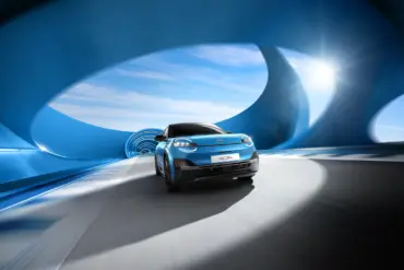 Frontansicht des neuen blauen Nissan Micra beim Fahren durch einen modern designten blauen Tunnel mit Sonnenlicht