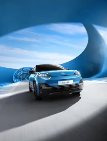 Frontansicht des neuen blauen Nissan Micra beim Fahren durch einen modern designten blauen Tunnel mit Sonnenlicht