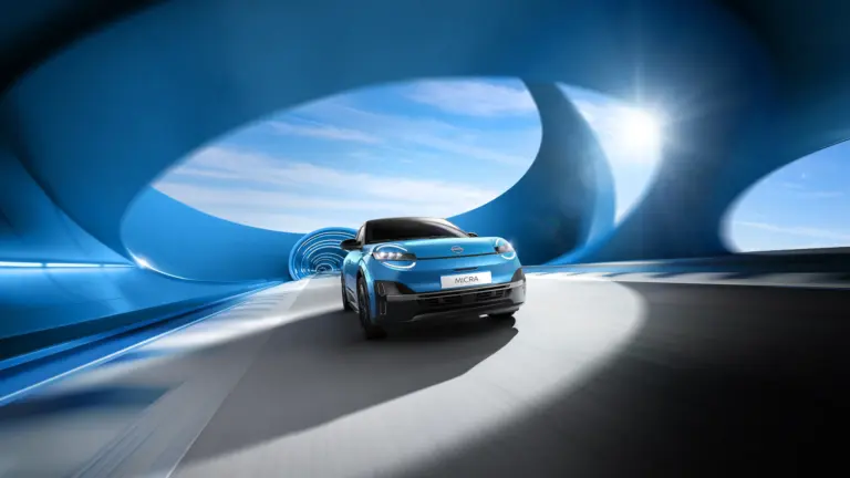 Frontansicht des neuen blauen Nissan Micra beim Fahren durch einen modern designten blauen Tunnel mit Sonnenlicht