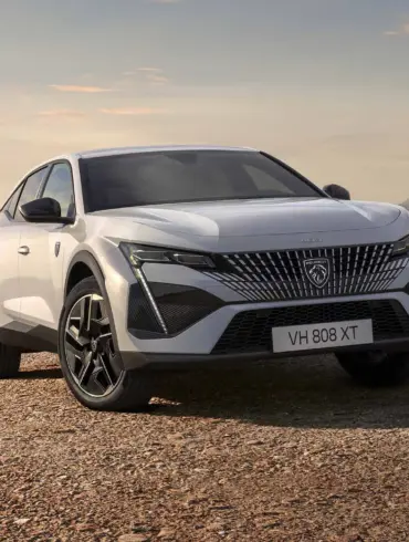 Der neue Peugeot E-408 als vollelektrisches Fastback-Modell in weißer Lackierung auf offenem Gelände vor bergiger Kulisse.