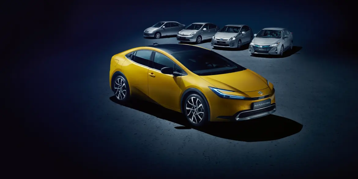 Toyota Prius Plug-in Hybrid in Gelb, umgeben von älteren Prius-Generationen, auf dunklem Untergrund.