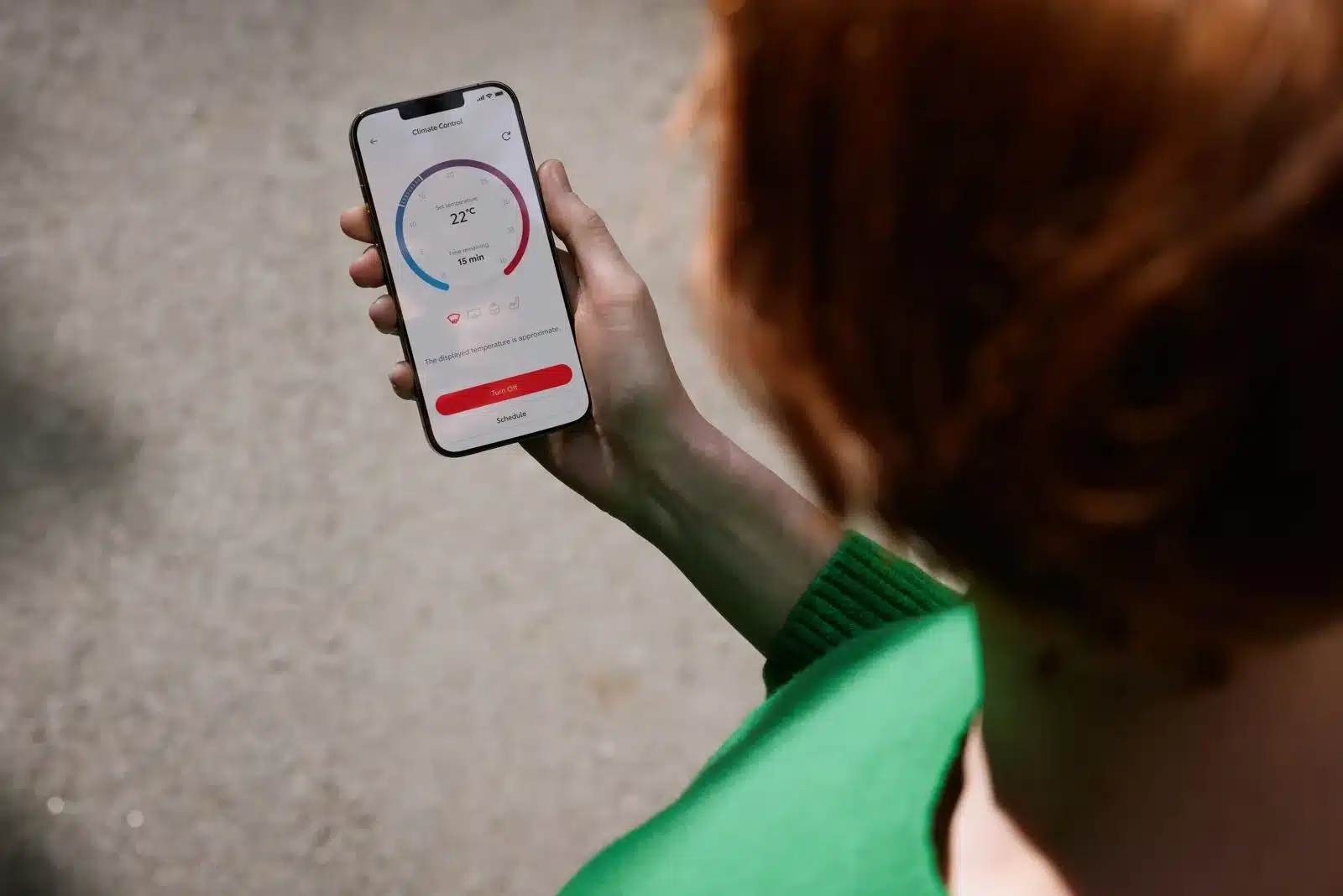Person hält Smartphone mit geöffneter MyToyota-App zur Steuerung der Fahrzeugklimatisierung.
