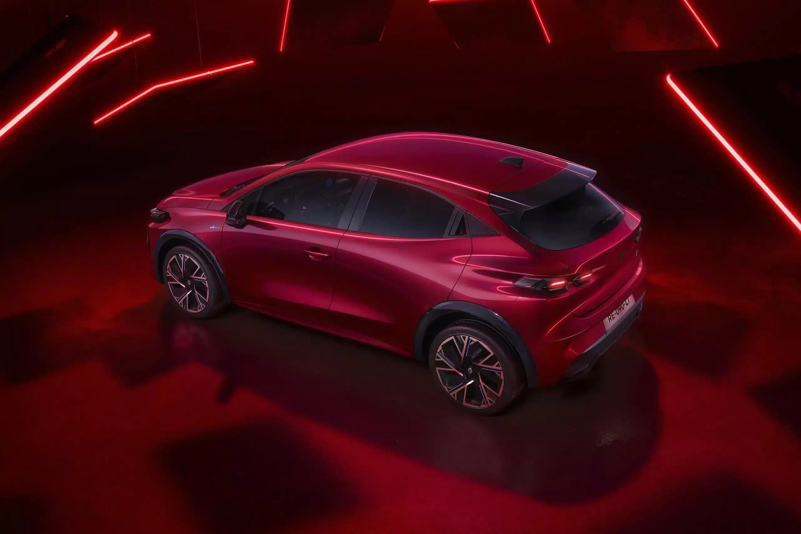 Nouvelle Renault Clio Full Hybrid E-Tech in roter Lackierung aus schräger Rückansicht vor futuristischem Hintergrund