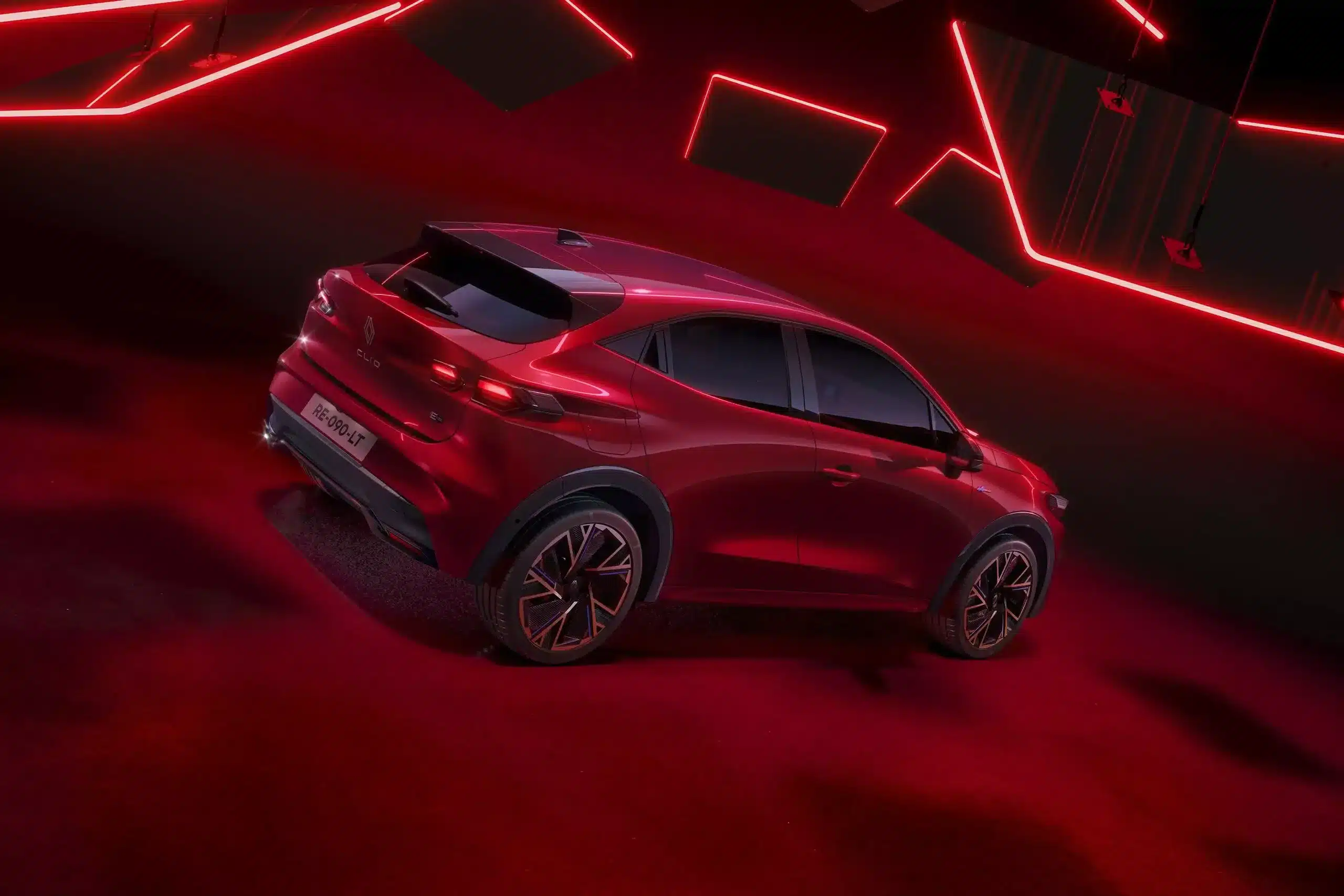 Heck- und Seitenansicht des neuen Renault Clio Full Hybrid E-Tech in Rot, präsentiert vor einer roten, futuristischen Beleuchtung