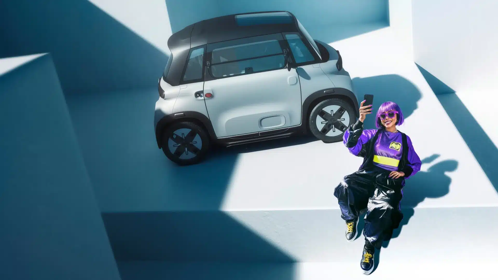 Opel Rocks City-Stromer mit junger Frau vor minimalistischem, urbanem Hintergrund