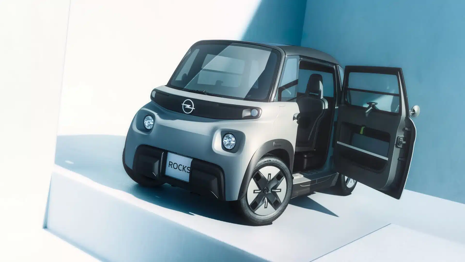 Opel Rocks Elektroauto mit geöffneter gegenläufiger Tür in hellblauer Umgebung