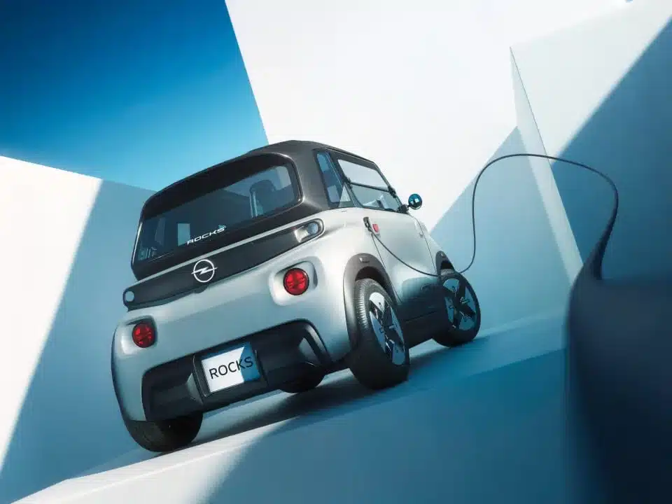 Heckansicht eines Opel Rocks-e beim Ladevorgang an einer Wand in moderner Architektur.