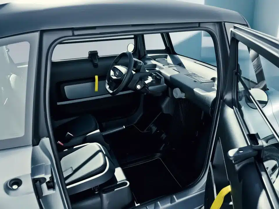 Innenaufnahme des Opel Rocks-e mit geöffneten Türen, zeigt Lenkrad, Sitze und minimalistischen Innenraum