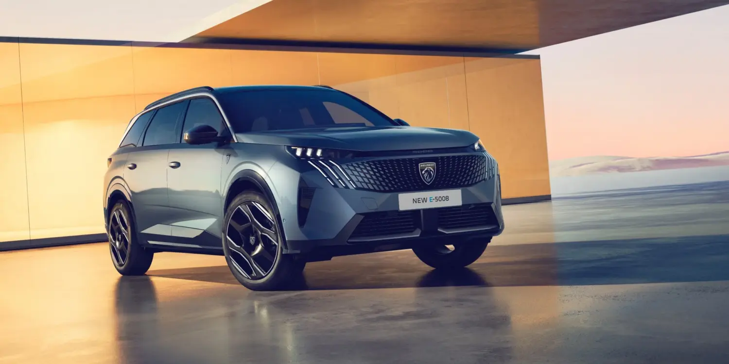 Peugeot 5008 Hybrid in Seitenansicht mit markantem Kühlergrill und moderner Linienführung, stehend in heller Architekturkulisse.