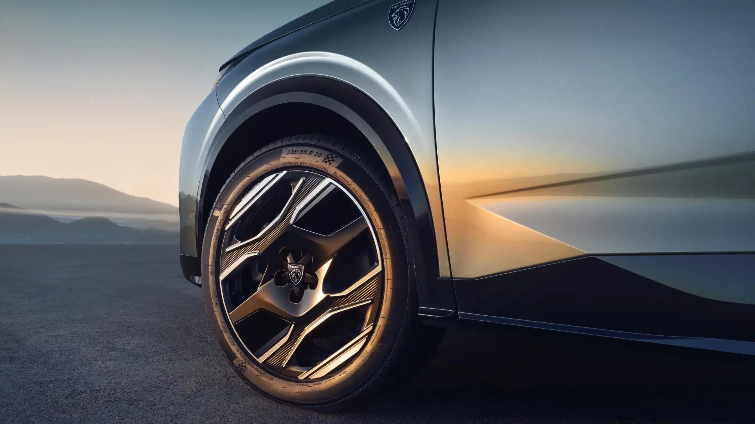 Detailansicht des Vorderrads am Peugeot 5008 Hybrid mit Logo und Designerfelge bei Sonnenuntergang