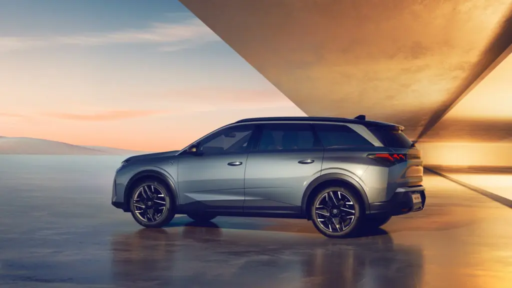 Peugeot 5008 Hybrid in Seitenansicht vor moderner Architektur bei Sonnenuntergang