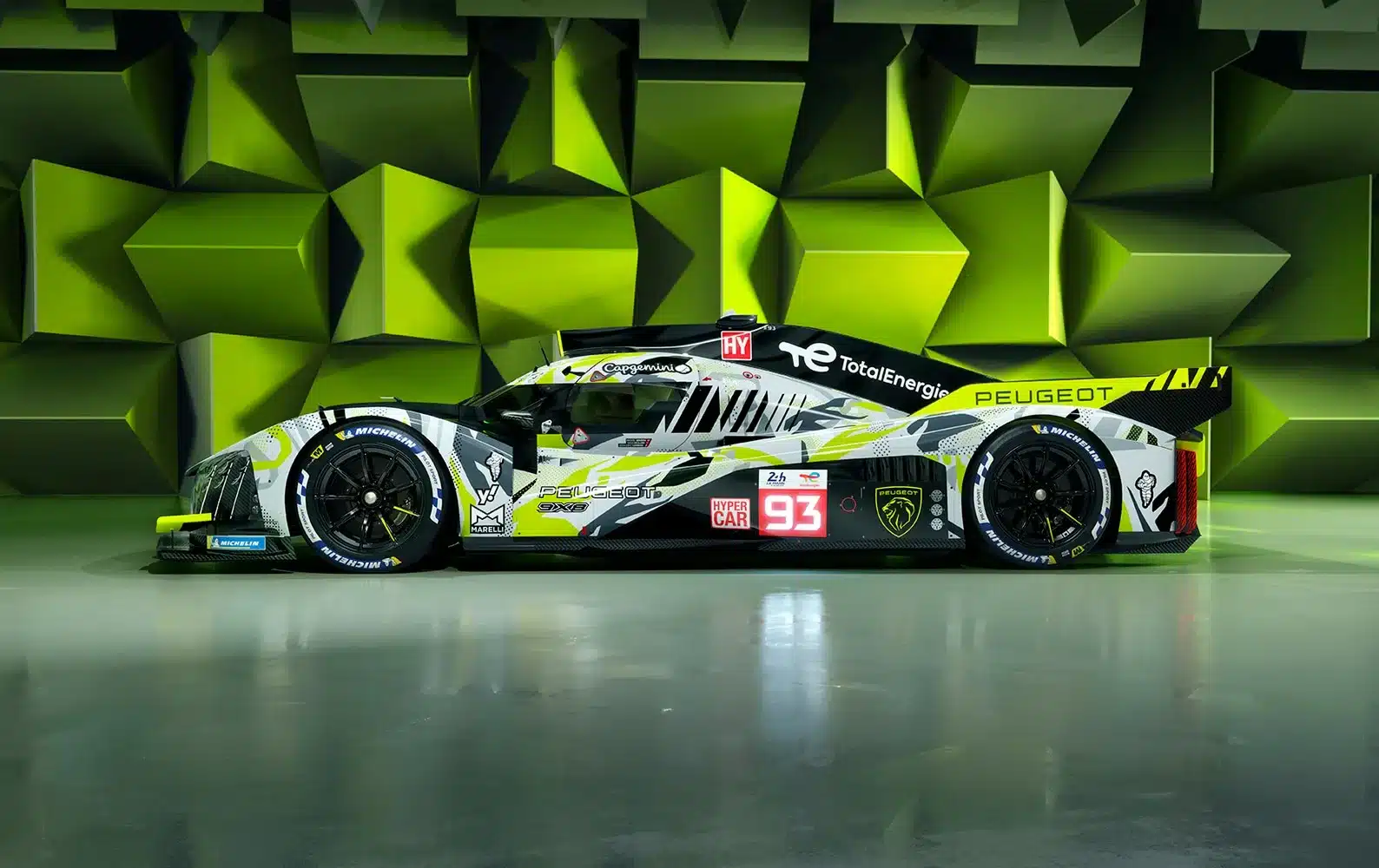 Peugeot 9X8 Art Car Version, Seitenansicht mit auffälliger Lackierung und Sponsorenlogos in grün-gelber Studiokulisse.