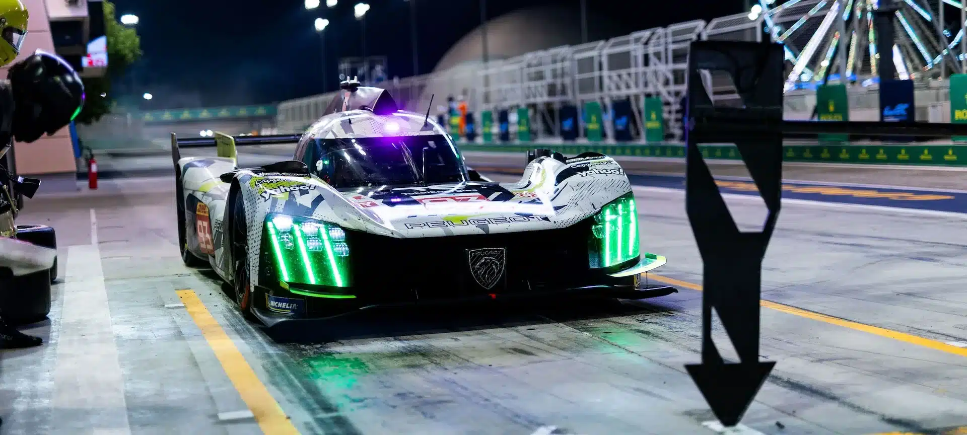 Peugeot 9X8 Hypercar im Boxenstopp bei Nacht mit leuchtenden LED-Scheinwerfern und Löwenemblem