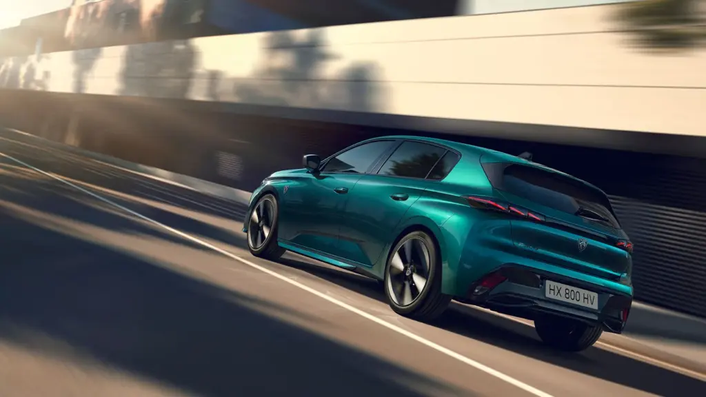 PEUGEOT E-308 in Grün fährt dynamisch auf moderner Straße