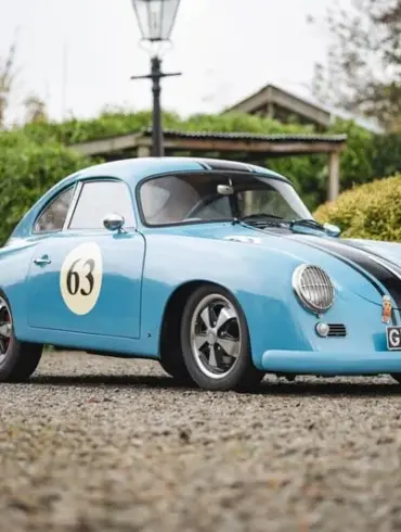 Blauer Porsche 356 Outlaw Tribute mit schwarzen Rennstreifen und Startnummer 63, fotografiert im Freien auf einem Kiesweg.