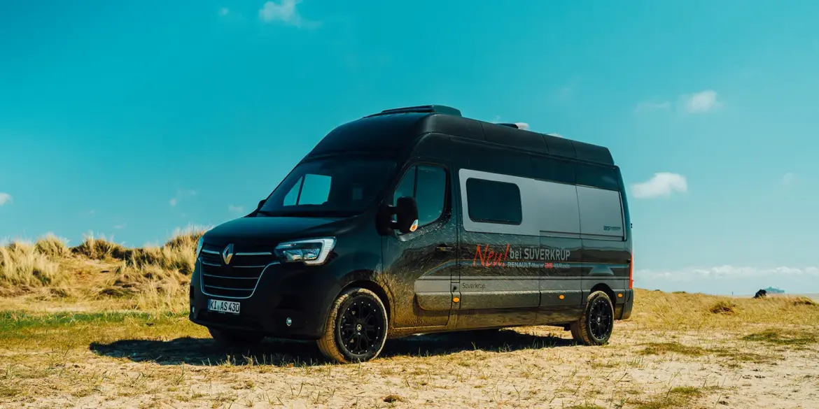 Renault Master VANtastic Campervan steht auf sandigem Gelände unter blauem Himmel.