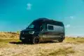 Renault Master VANtastic Campervan steht auf sandigem Gelände unter blauem Himmel.