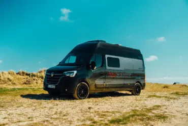 Renault Master VANtastic Campervan steht auf sandigem Gelände unter blauem Himmel.