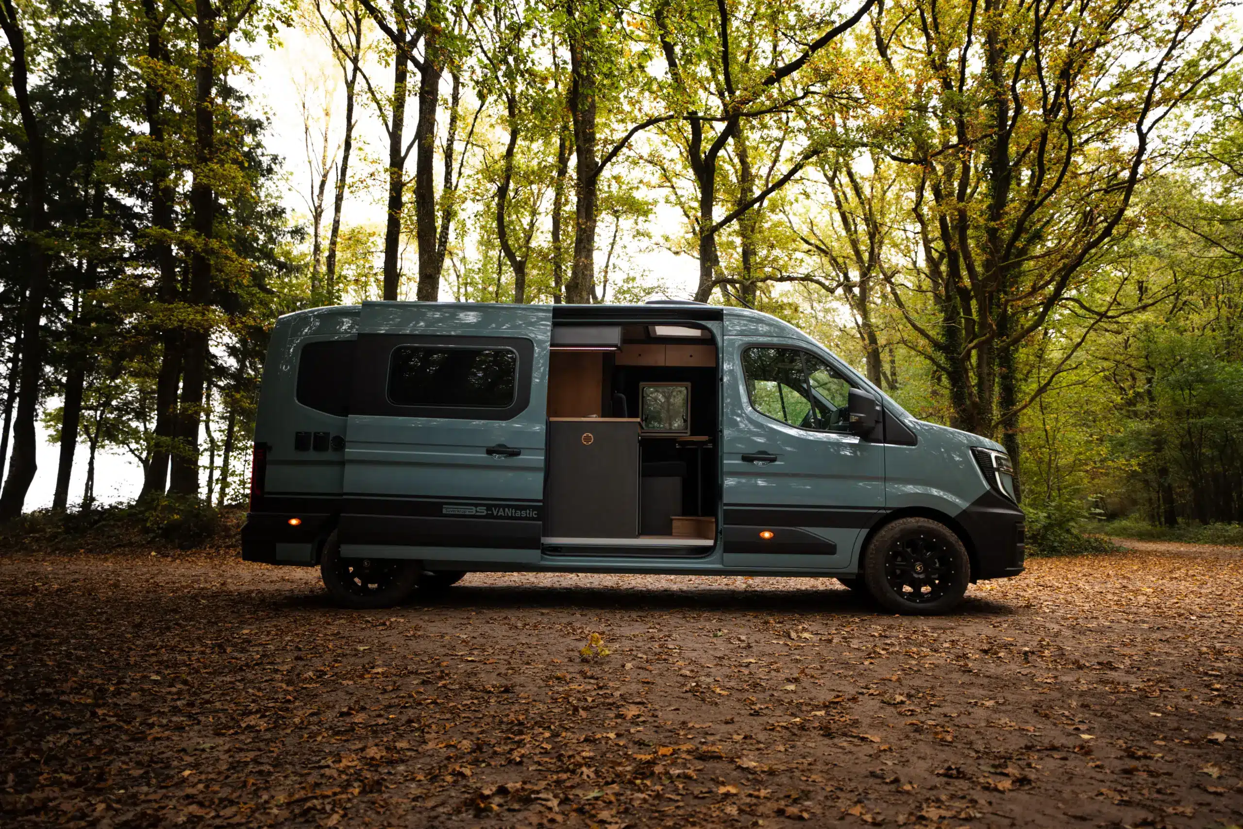 Renault Master VANtastic Campervan mit geöffneter Seitentür im Wald, Ansicht von der Seite.