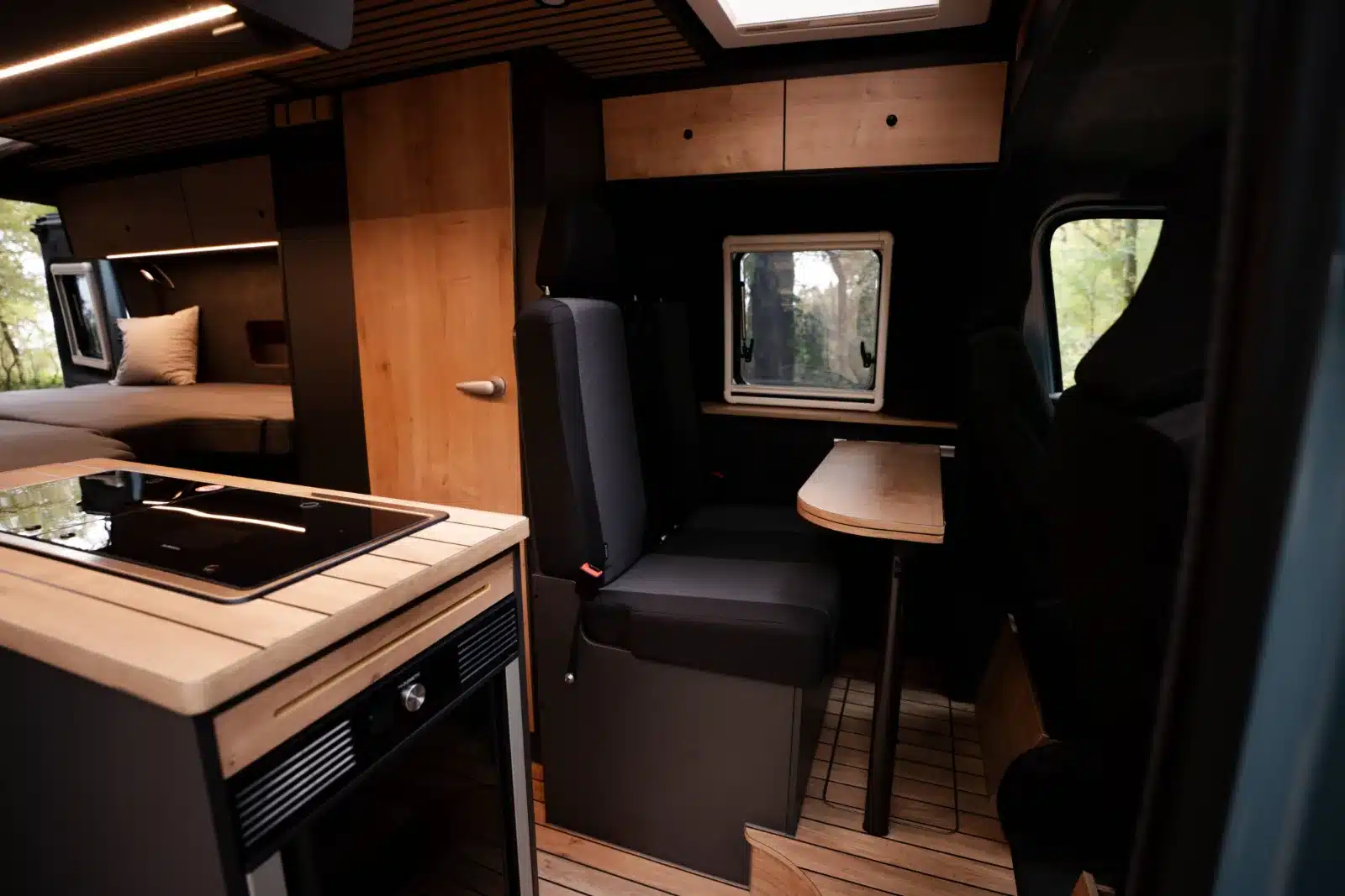 Hochwertig ausgebauter Innenraum eines Renault Master VANtastic mit Küchenblock, Sitzgruppe und Längsbett
