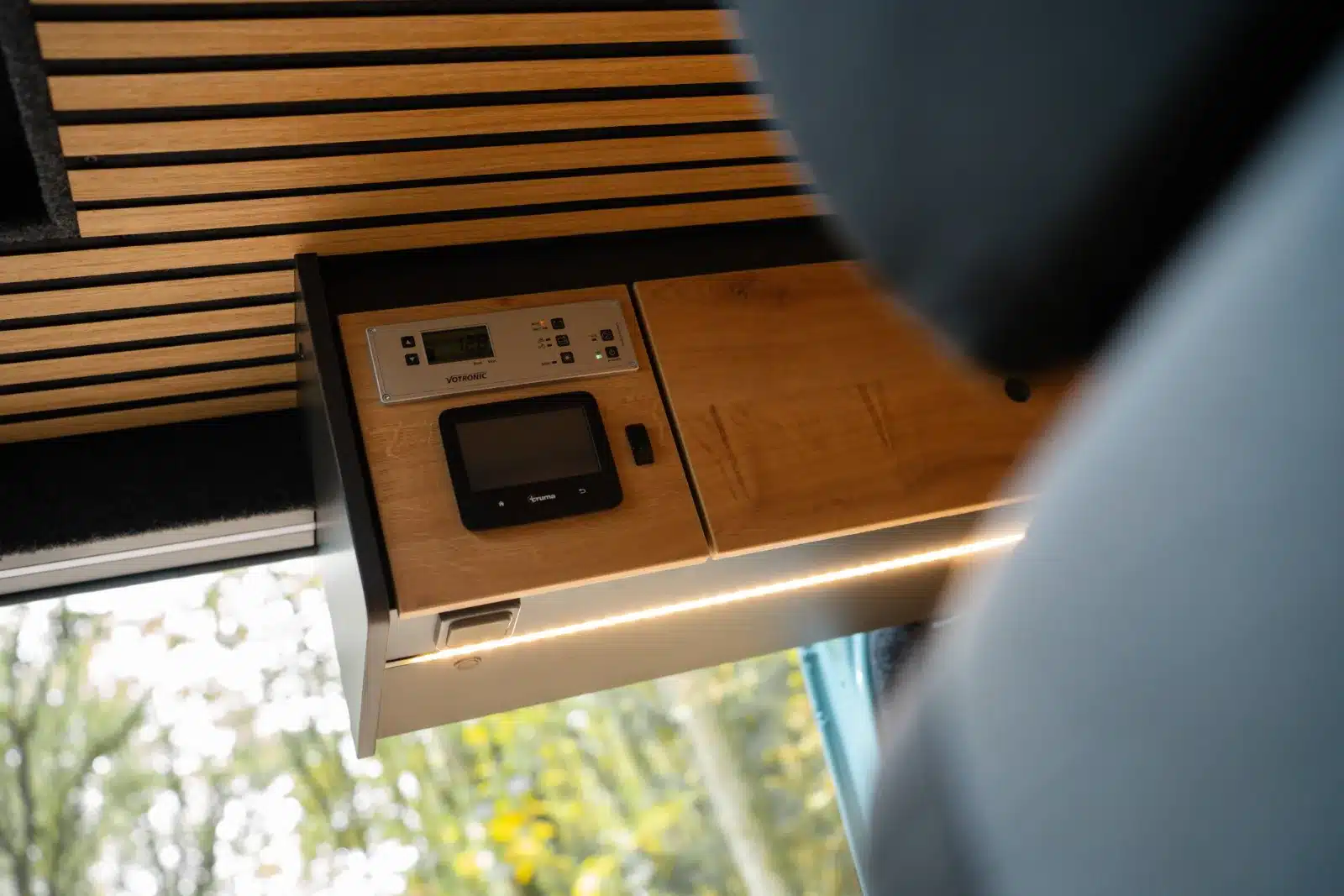 Kontroll- und Bedienelemente im Innenraum des Renault Master VANtastic mit Holzverkleidung und LED-Beleuchtung.
