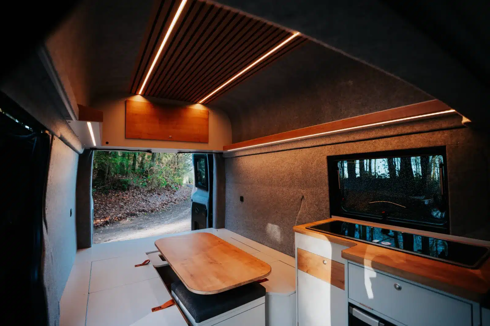 Wohnraum und Küche im Renault Trafic BS-CAMP, Camper-Ausbau mit Tisch, Sitzbank und Küchenzeile