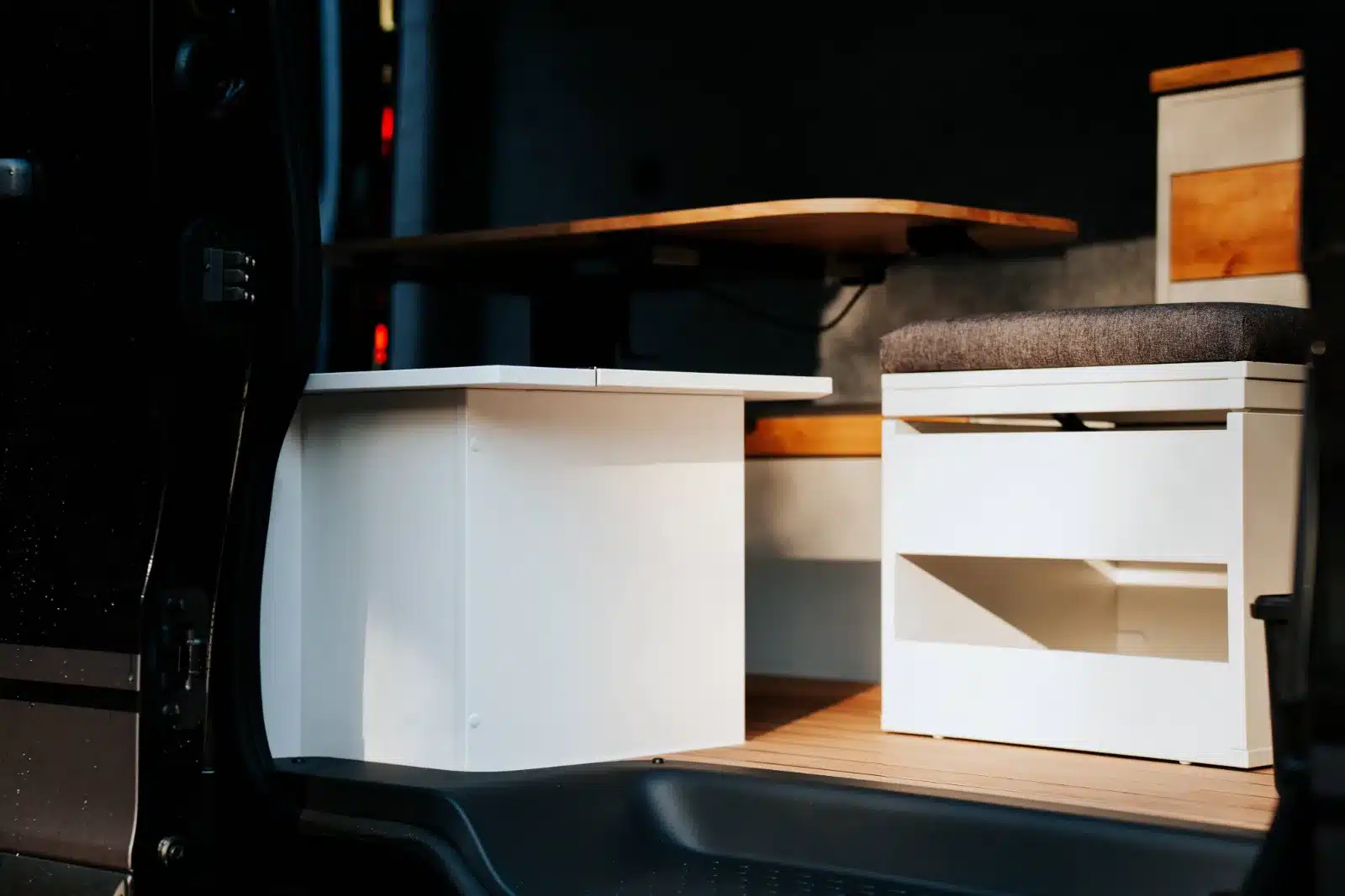 Moderner Sitz- und Wohnbereich im Innenraum des Renault Trafic BS-CAMP mit weißer Sitzbank und Holztisch