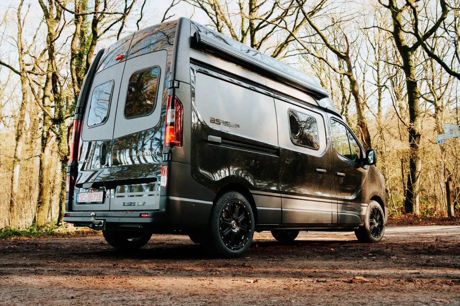 Seiten- und Heckansicht des Renault Trafic BS-CAMP Campervans auf einem Waldweg.