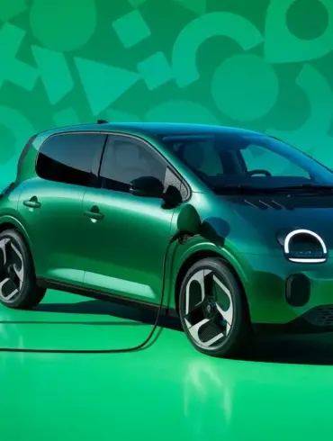 Renault Twingo E-Tech Electric beim Ladevorgang an einer öffentlichen Ladesäule vor grünem Hintergrund