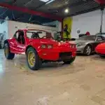 Volkswagen Deserter GT Buggy von 1970 in Rot mit goldenen Felgen in einer Fahrzeughalle