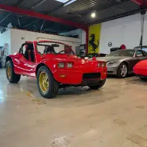 Volkswagen Deserter GT Buggy von 1970 in Rot mit goldenen Felgen in einer Fahrzeughalle
