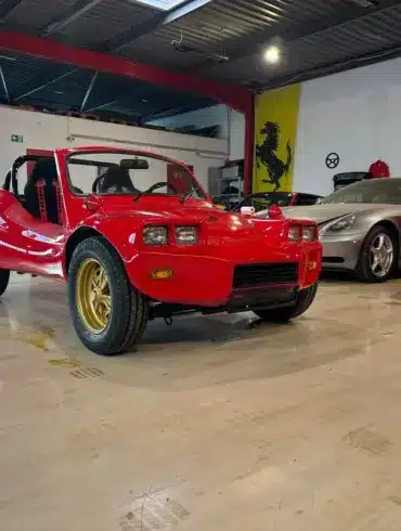 Volkswagen Deserter GT Buggy von 1970 in Rot mit goldenen Felgen in einer Fahrzeughalle