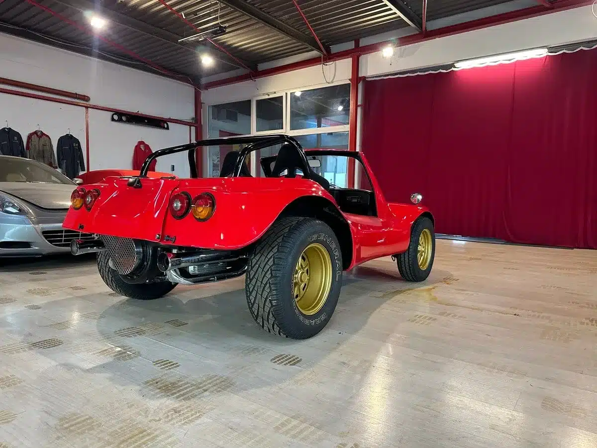 Roter Volkswagen Deserter GT Buggy von 1970 mit goldenen Felgen und offenem Heck in einer Halle