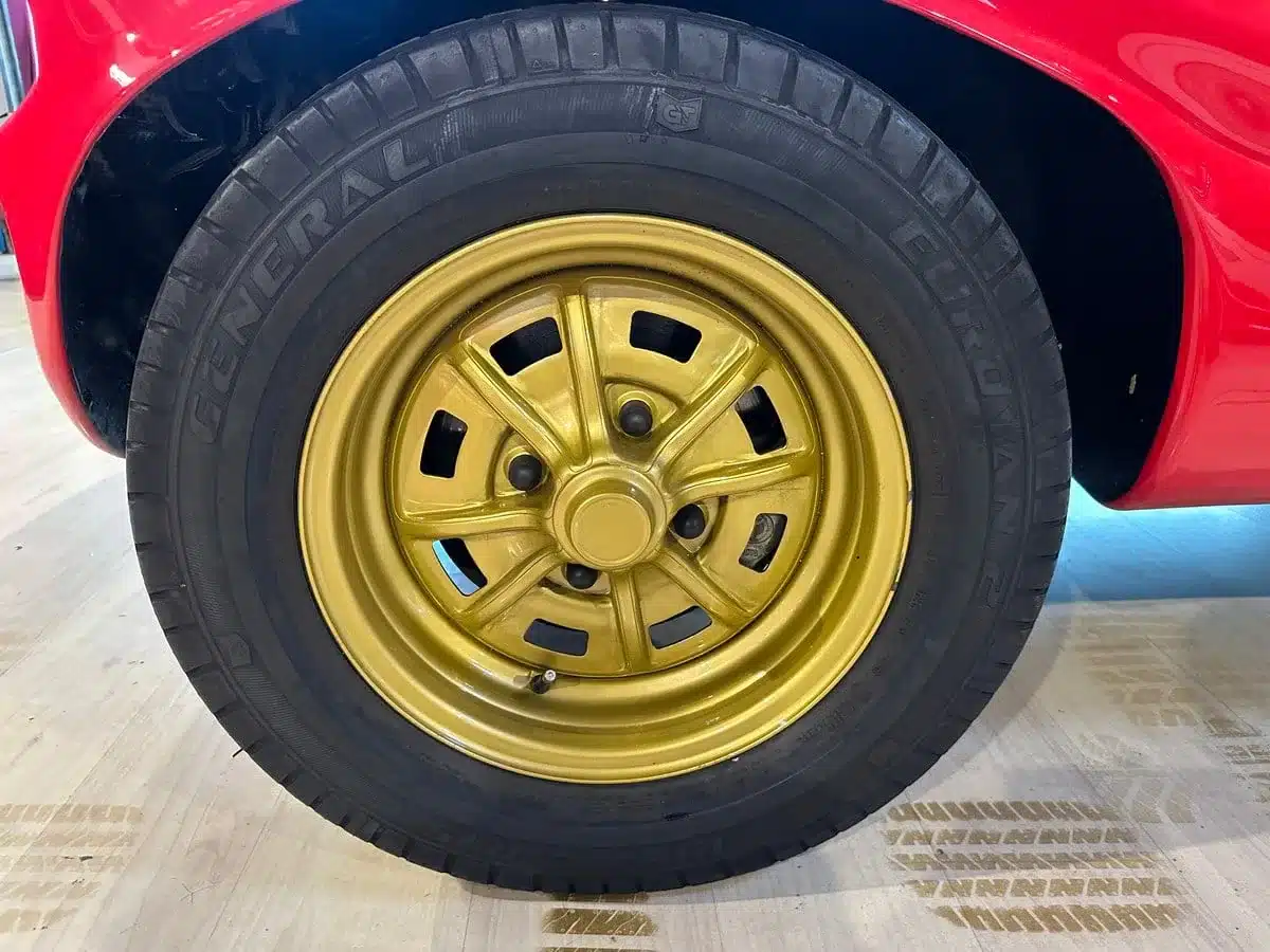 Goldfarbenes Rad mit Reifen am roten Volkswagen Deserter GT Buggy von 1970, Nahaufnahme