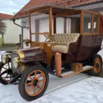 Klassischer Oldtimer mit Holzrahmen und edlen Details, stehend auf verschneitem Hof vor einer Garage