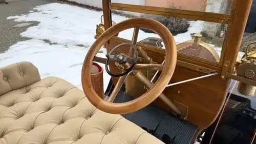 Innenraum eines liebevoll restaurierten Oldtimers mit Holzlenkrad und beigefarbenen Polstersitzen