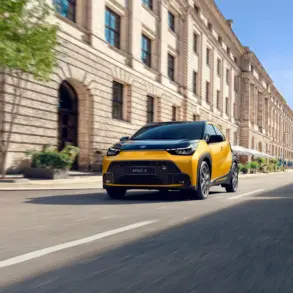 Toyota Aygo X Hybrid in Gelb fährt durch eine Innenstadt mit historischen Gebäuden